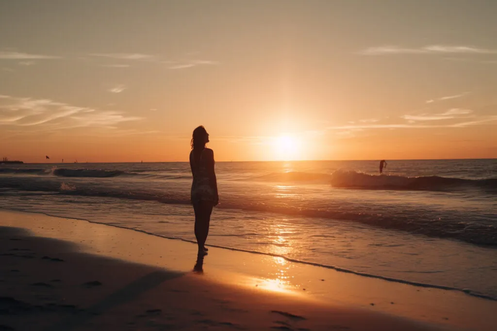 A person watching the sunset from a sandy beach, from the original coastal-activities article.