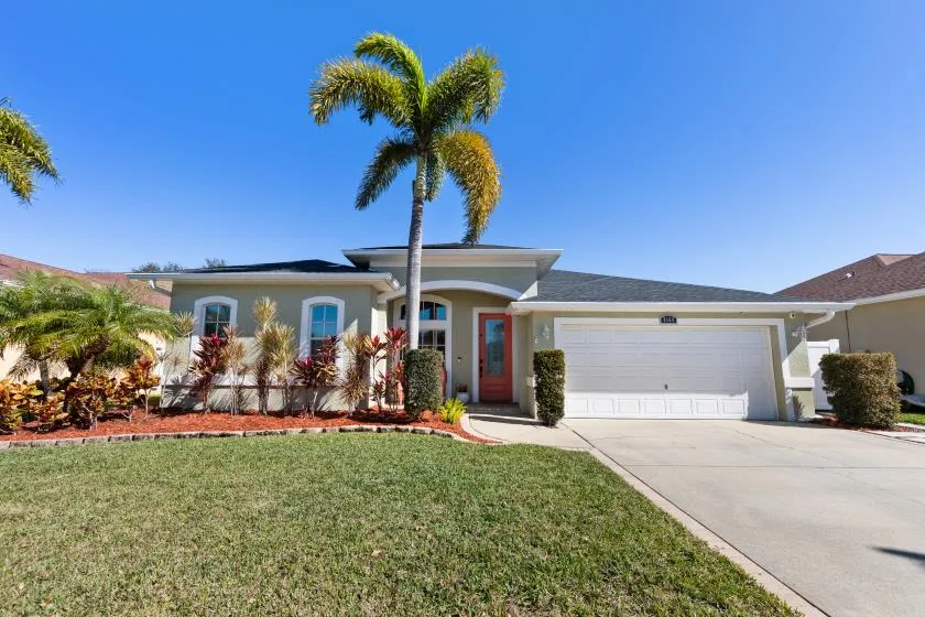 A single-story home with palms and a landscaped front yard