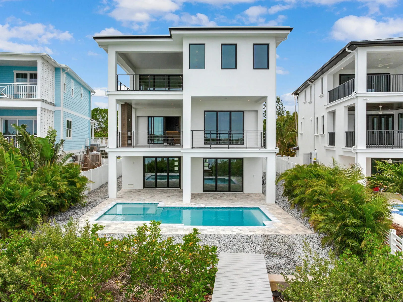 White coastal home with balconies, a pool and tropical landscaping, supplied by Heidi